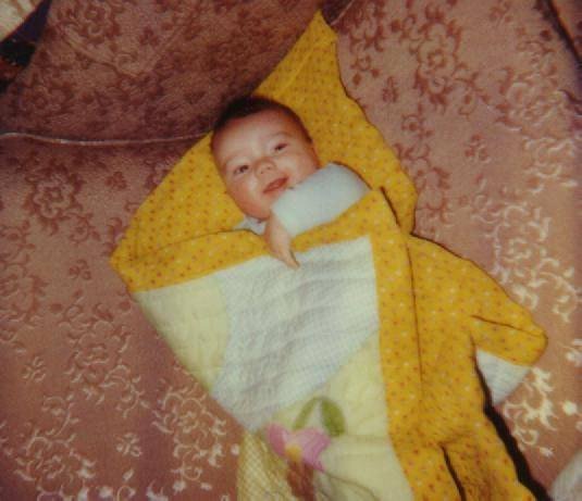 Scott as a newborn, wrapped in a yellow blanket.