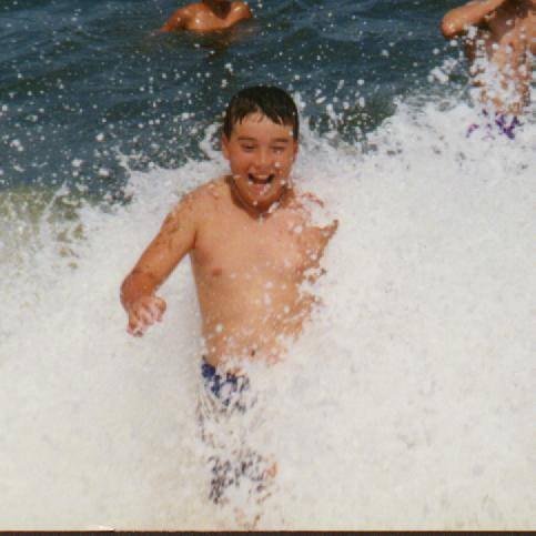 Scott laughing and splashing in ocean waves.